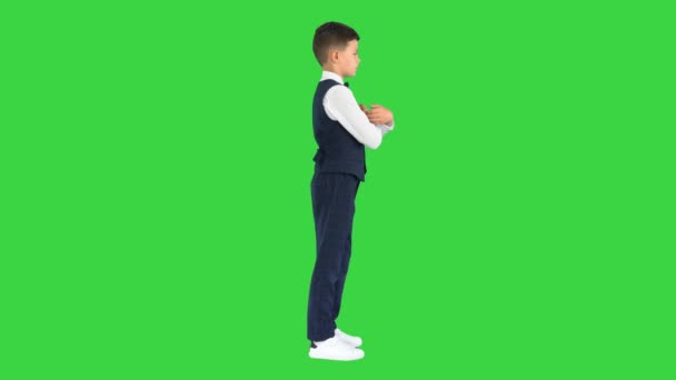 Menino confiante em gravata borboleta e colete cruzando os braços e colocando as mãos em seus bolsos em uma tela verde, Chroma Key. — Vídeo de Stock