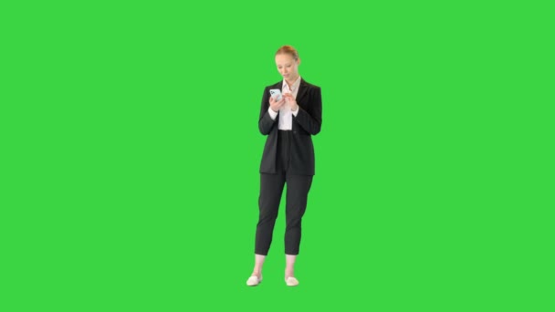 Χαμογελαστή επιχειρηματίας στέκεται και χρησιμοποιώντας το κινητό τηλέφωνο σε μια πράσινη οθόνη, Chroma Key. — Αρχείο Βίντεο
