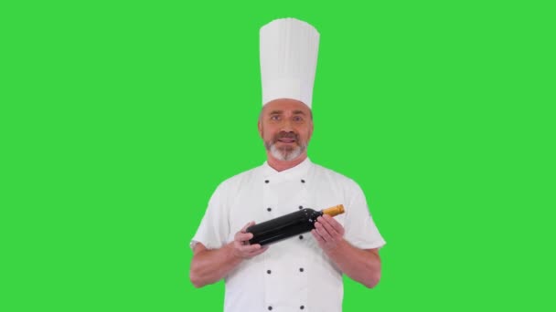 Chef en uniforme sosteniendo una botella de vino y hablando de ello con usted en una pantalla verde, Chroma Key. — Vídeos de Stock