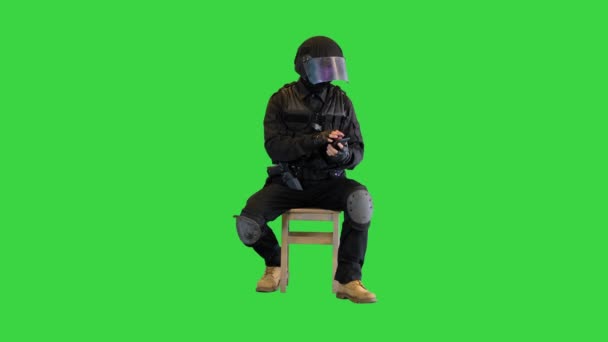 Riot policeman sitting and using smartphone on a Green Screen, Chroma Key. — Stock Video