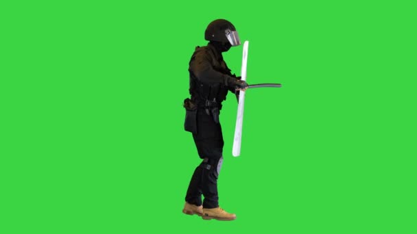 Riot policeman hitting shield with the baton while walking on a Green Screen, Chroma Key. — Stock Video