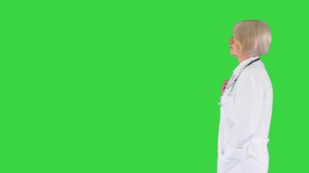 Зрелая женщина-врач, проходящая мимо по зеленому экрану, хрома-ключ. — стоковое видео
