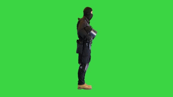 Bereitschaftspolizist mit Helm in der Hand auf einem Green Screen, Chroma Key.