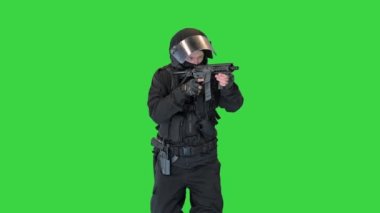 Tüfekli bir polis memuru. Siyah üniformalı. Yeşil Ekran 'a nişan alıyor ve ateş ediyor..