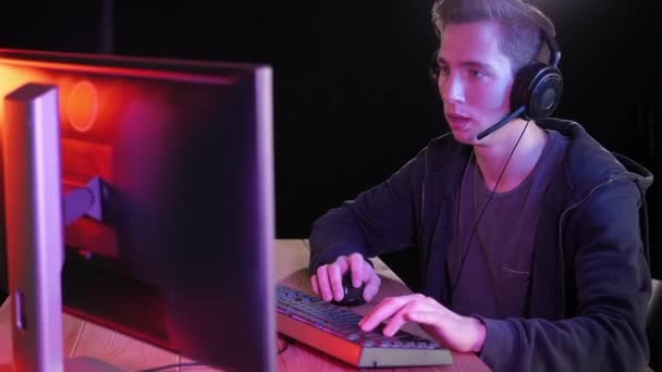 Молодые Handsome Pro Games играют в онлайн-видеоигру, общаются с игроками команды через микрофон. — стоковое видео