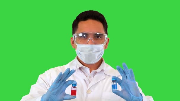 The doctor looking at the two new vaccines in ampoules and makes a choice showing the red one to camera on a Green Screen, Chroma Key. — Stock Video