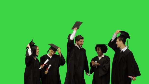 Счастливые друзья бросают выпускные люки в воздух на зеленом экране, Chroma Key. — стоковое видео