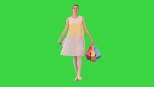 Młoda dziewczyna spaceruje w letniej sukience trzymając torby na zakupy na zielonym ekranie, Chroma Key. — Wideo stockowe