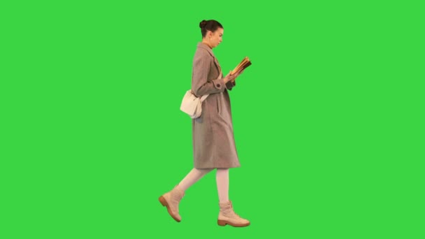 Młoda kobieta spacerująca i czytająca książkę na zielonym ekranie, Chroma Key. — Wideo stockowe