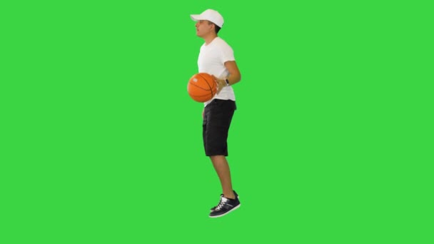 Молодой случайный человек прыгает баскетбольный мяч на зеленом экране, хрома ключ. — стоковое видео