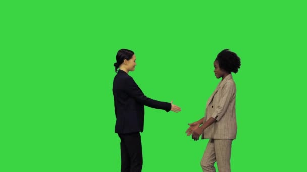 Ein Mädchen gratuliert dem anderen mit etwas und schüttelt ihr die Hand, dann drehen sie sich um und posieren für ein Foto auf einem Green Screen, Chroma Key. — Stockvideo