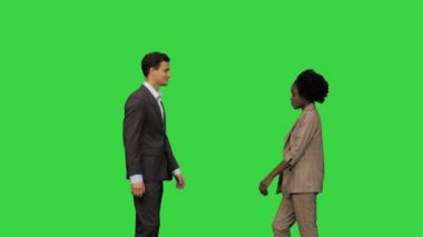 Genç bir beyaz adam ve iş kıyafetleri içinde genç bir Afrikalı Amerikalı kadın Yeşil Ekran, Chroma Key 'de el sıkışıyor..
