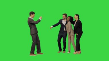 Takım elbiseli genç bir adam arkadaşlarının fotoğrafını çekiyor, onlar yeşil ekranda dans ederken, Chroma Key.