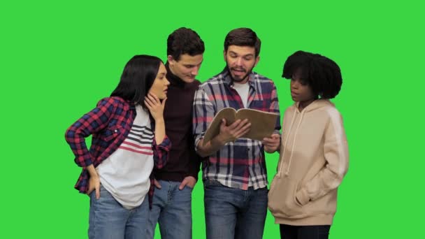 Молодой человек, читающий статью из журнала своим друзьям, они выглядят взволнованными на Зеленом экране, Chroma Key. — стоковое видео