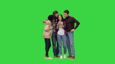 Bir grup arkadaş yeşil ekranda, Chroma Key 'de akıllı telefonlarıyla komik bir şeyi kontrol ediyor..