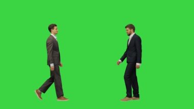 Takım elbiseli iki genç ve yakışıklı iş ortağı buluşup el sıkışıyor. Yeşil Ekran 'da tam boy bir video, Chroma Key..