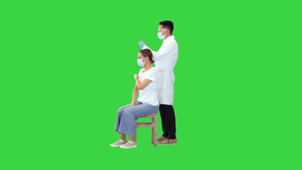 Lekarz wykonuje wstrzyknięcie szczepionki przeciw wirusowi covid-19 kobiecie na zielonym ekranie, Chroma Key. — Wideo stockowe