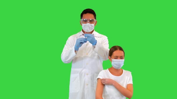 Arts die een injectie aan patiënt in een medisch masker op een groen scherm, Chroma Key. — Stockvideo