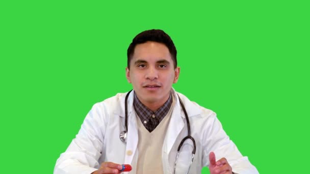 Positiv lege som holder en ampulle med vaksine som snakker i kamera på et grønt skjerm, kromatøkkel. – stockvideo