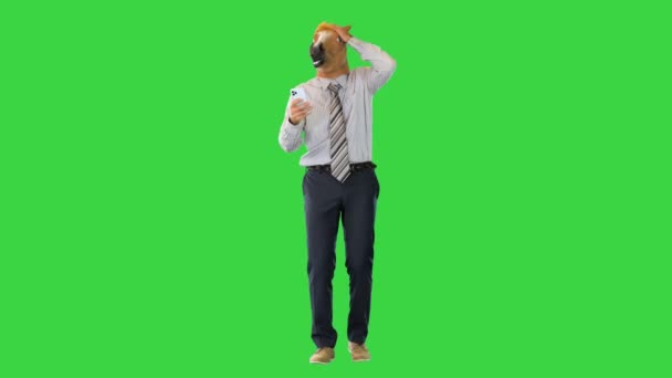 Forretningsmand med hestehoved er chokeret, mens du går og bruger smartphone på en grøn skærm, Chroma Key. – Stock-video