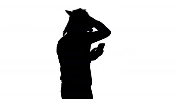 Silueta Podnikatel hlava koně je šokován při chůzi a pomocí smartphonu. — Stock video