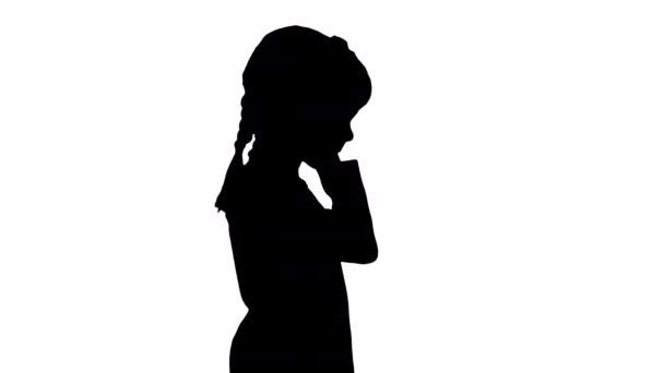 Silhouette Niña vestida de blanco caminando con auriculares y asintiendo con la cabeza al ritmo de la música. — Vídeos de Stock