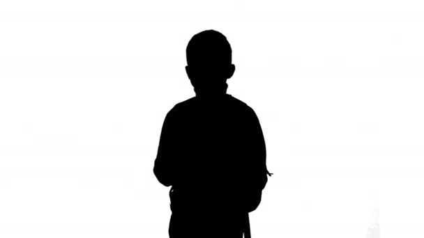 Silhouette Boy in polo neck walking with a backpack looking at camera. — Stock Video