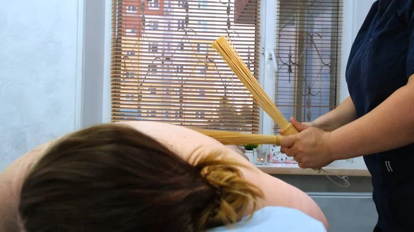 Massage therapeut maakt een anti-cellulitis massage aan een dikke vrouw op een massagetafel in een spa met een bamboe stick. Spa behandelingen. Gezondheid en schoonheid, voeding — Stockfoto