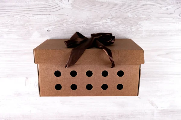 Pudełko kartonowe z brązowym łukiem na białym drewnianym stole, koncepcja usługi dostawy — Zdjęcie stockowe