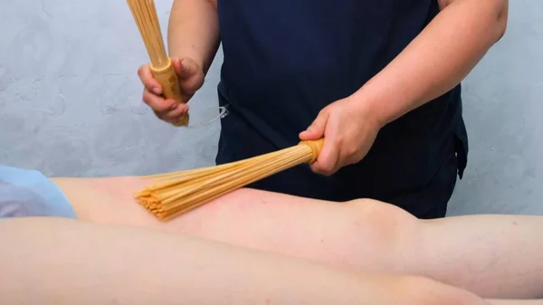 Massage therapeut maakt een anti-cellulitis benen massage aan een dikke vrouw op een massagetafel in een spa met een bamboe stok. Spa behandelingen. Gezondheid en schoonheid, voeding — Stockfoto