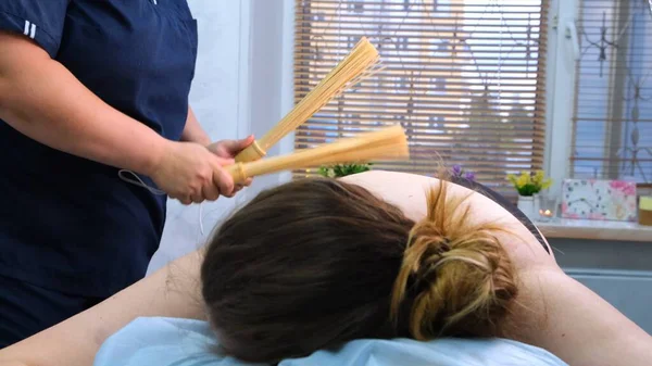 Masaj terapisti, masaj masasındaki şişman bir kadına bambu çubuğuyla anti-selülit masajı yapıyor. Spa tedavileri. Sağlık ve güzellik, diyet — Stok fotoğraf