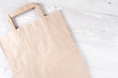Beyaz ahşap bir masada kahverengi bir kağıt torba. Logonuz için yer.