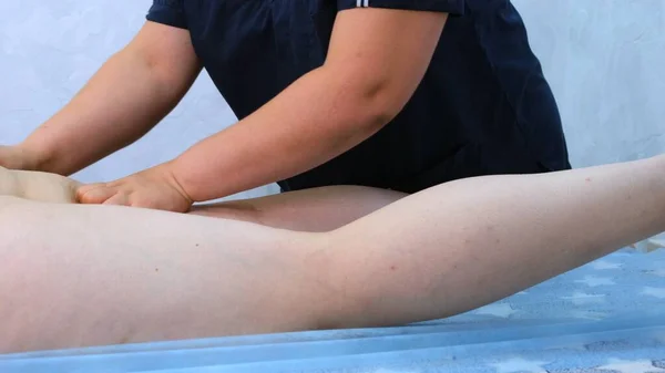 Terapeuta hace un masaje anti-celulitis. Masajista masajeando gruesas piernas femeninas en el salón de belleza. Concepto de tratamiento de belleza. primer plano —  Fotos de Stock