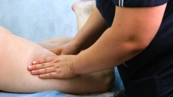 Terapeuta faz uma massagem anti-celulite. Massagista massageando pernas femininas grossas no salão de beleza. Conceito de tratamento de beleza. close-up — Fotografia de Stock