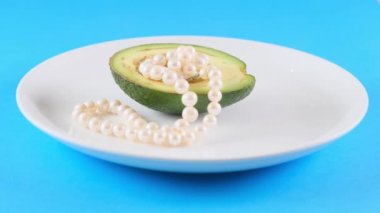 Beyaz tabakta incili yarım avokado ve mavi arka planda duman. Modaya uygun yemek tasarımı..