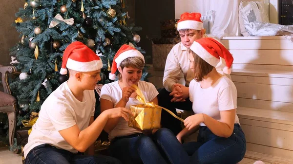 Rodzina w Boże Narodzenie kapelusze wymiany prezentów przed choinką. — Zdjęcie stockowe