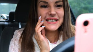 Araba sürerken akıllı telefon kullanan neşeli bir kadın. Araba kullanırken telefona bakan neşeli bir kadının portresi..