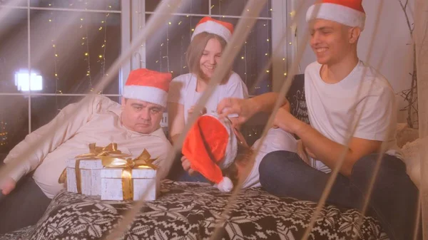 Family in Christmas hats exchanges gifts. — Stock Photo, Image