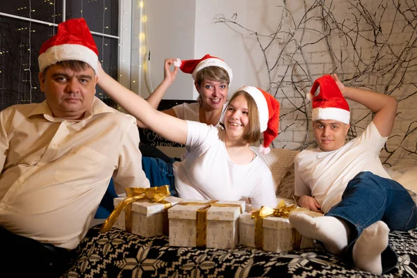 Family in Christmas hats exchanges gifts. — Stock Photo, Image