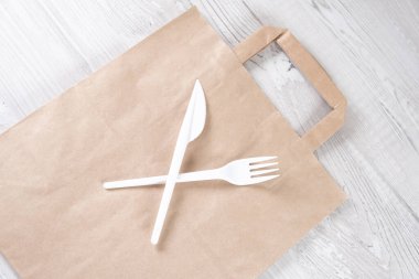 Plastik çatal, kağıt torbada bıçak. Çevre dostu gıda ambalajları ve gri arka planda fotokopi alanı olan pamuk eko torbaları. Doğanın işleyişi ve geri dönüşüm konsepti. Yemek konteynırları ve hızlı sokak yemekleri.