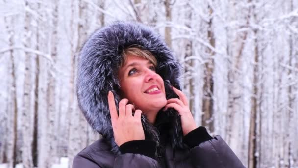 Winter portrait of a young beautiful brunette woman in a winter jacket with fur. Snow winter beauty concept — Stock Video