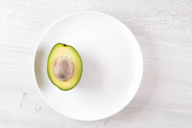 Beyaz tabakta yarım taze avokado meyvesi