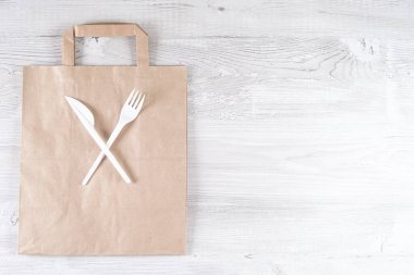 Plastik çatal, kağıt torbada bıçak. Çevre dostu gıda ambalajları ve gri arka planda fotokopi alanı olan pamuk eko torbaları. Doğanın işleyişi ve geri dönüşüm konsepti. Yemek konteynırları ve hızlı sokak yemekleri.