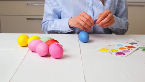 Kobiece dłonie malują jajka w pastelowych kolorach na Wielkanoc i zdobią je ptakami w wystroju, siedząc przy stole w kuchni lub w pracowni artystycznej, kopiując przestrzeń — Wideo stockowe