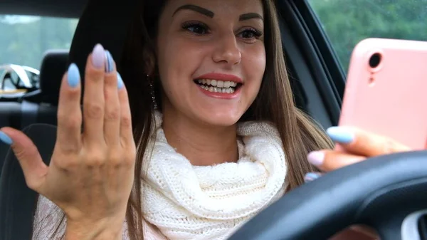 Радостная женщина, пользующаяся смартфоном за рулем автомобиля. Портрет веселой женщины, смотрящей в телефон за рулем. — стоковое фото