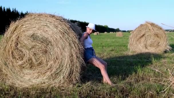 Bella ragazza in un cappello spinge un pagliaio. Zona rurale. Femminista concetto di donna forte — Video Stock