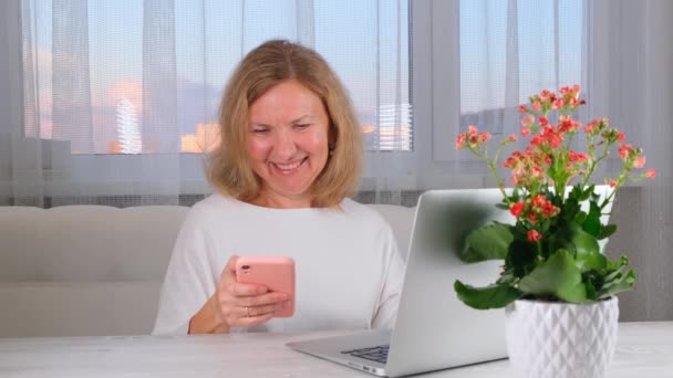 Γυναίκα που χρησιμοποιεί φορητό υπολογιστή και κινητό τηλέφωνο στο σπίτι, κάνει online αγορές, freelance work. — Αρχείο Βίντεο