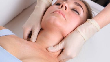 Güzellik salonunda yüz masajı yapan genç bir kadının çene masajı.