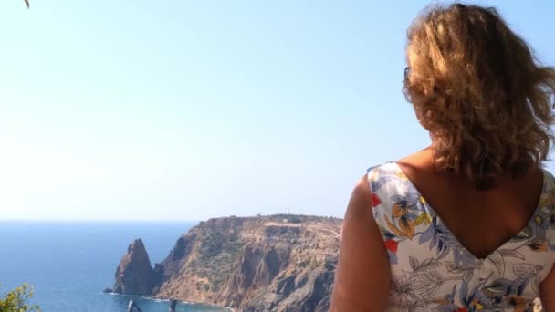 Frau bewundert einen schönen Blick auf die Küste des türkisfarbenen Meeres und die Berge am Kap Fiolent, Krim. — Stockvideo