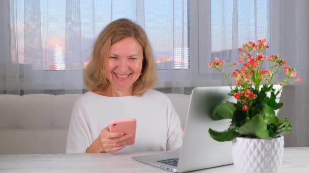 Mulher usando laptop e telefone celular em casa, fazendo compras online, trabalho freelance. — Vídeo de Stock